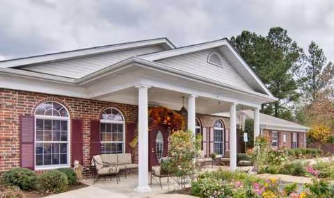 Front exterior of Southern Oaks senior living facility with brick facade, columns, and porch seating.