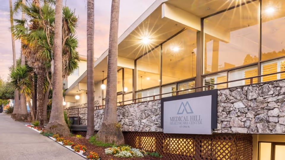 Exterior view of Medical Hill Healthcare Center with palm trees and decorative landscaping.