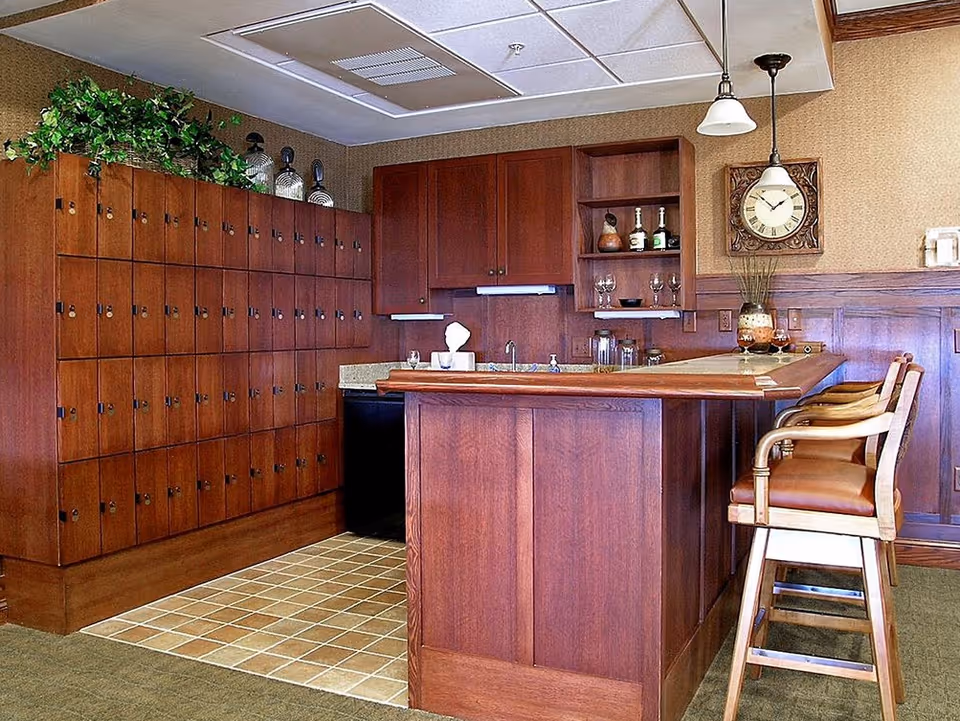 Wood-paneled communal bar area with lockers, shelving, a wall clock and bar stools.