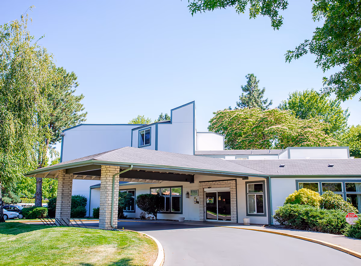 Front exterior of a modern senior living facility with a covered entrance and landscaped surroundings.