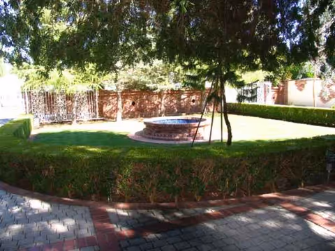 A landscaped outdoor courtyard with a circular fountain and trimmed hedges.