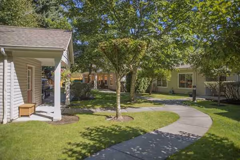 Exterior view of Rosewood Courte with curved walkway, trees, and light-gray buildings.