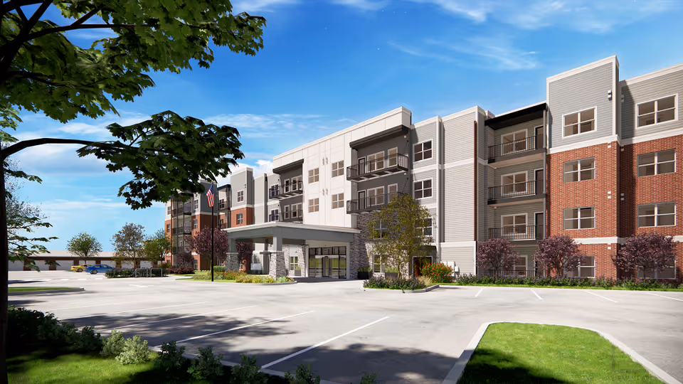 Exterior view of a modern senior living building with entrance and parking.