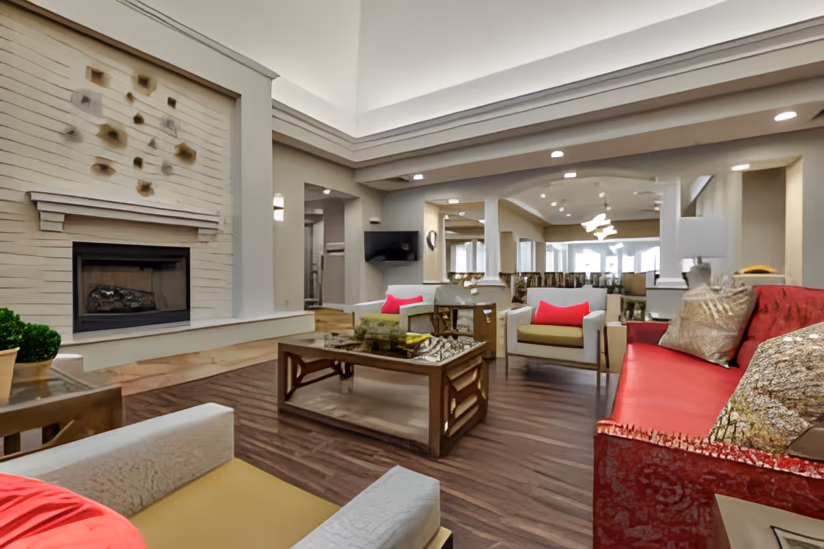 Bright communal living room with a fireplace, sofas and armchairs arranged around a central coffee table.