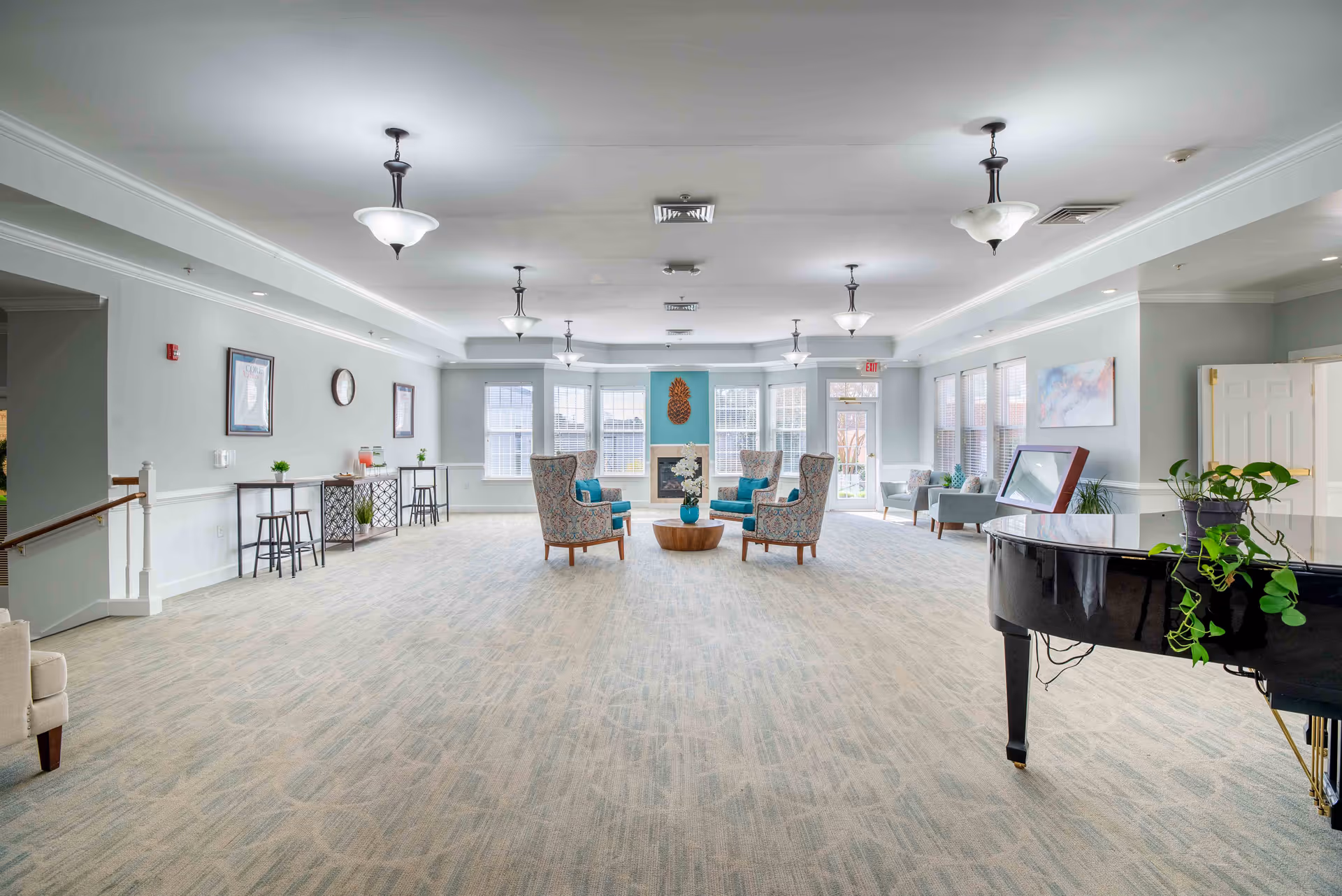 Bright, spacious common lounge with seating arrangements, a grand piano, and large windows.