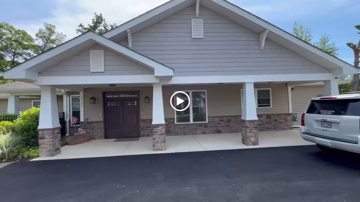 Front entrance of Evermore Senior Living showing a covered porch with double doors, stone-clad columns, and a parked SUV.