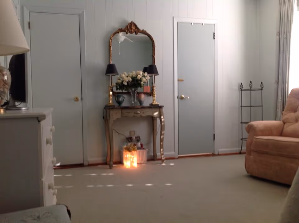 Living room with a decorative console table and mirror between two doors, a beige recliner on the right, and a glowing lantern on the floor.