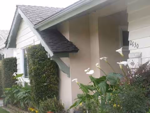 A light-beige senior living facility exterior entrance with shrubs and flowers.