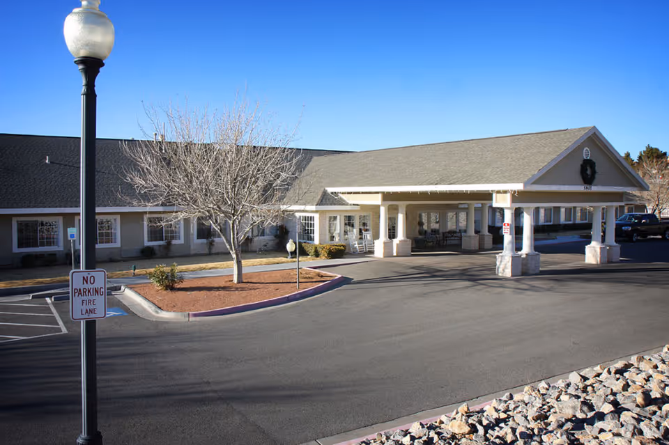 Front exterior of SunRidge at Desert Springs showing a covered entrance/porte-cochere, a leafless tree, parking area and a lamp post with a 'No Parking Fire Lane' sign.