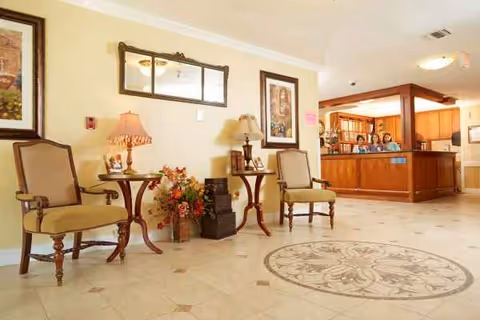 Senior living facility lobby with two chairs, lamps, artwork, and reception desk.