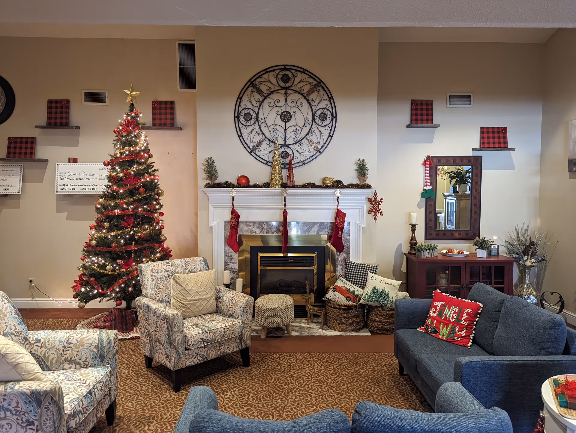 Seasonally decorated living room with a Christmas tree, a fireplace with stockings, armchairs and sofas.