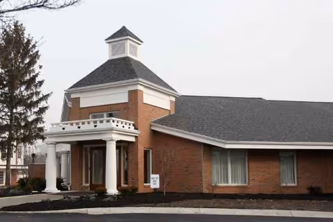 Brick senior living facility with a columned entrance and pitched roof.