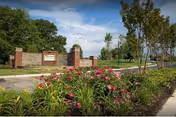 Entrance sign for Asbury Place Maryville surrounded by a landscaped garden with pink flowers and green shrubs under a partly cloudy blue sky.