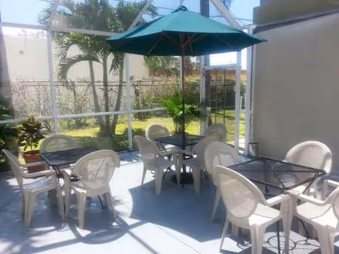 Outdoor patio at a senior living facility with seating under a green umbrella.