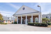 Front view of a light-colored senior living facility with a portico entrance.