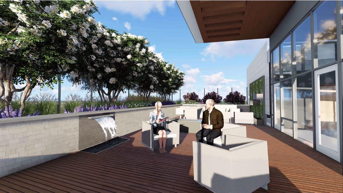 Rooftop terrace with outdoor seating, a water feature, landscaping, and two people seated near a building's glass facade.