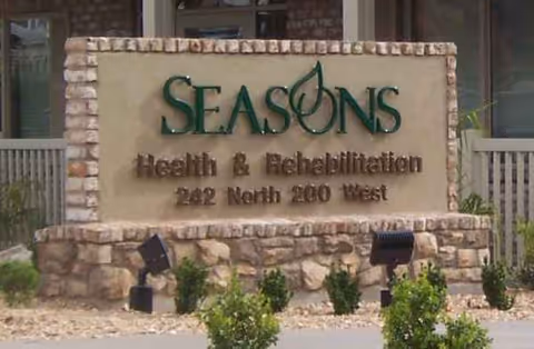 Stone sign for Seasons Health & Rehabilitation located at 242 North 200 West, surrounded by small bushes and outdoor lighting fixtures.
