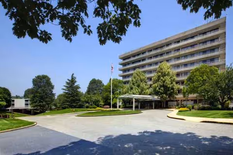 Exterior view of a multi-story senior living building with a circular driveway and greenery.
