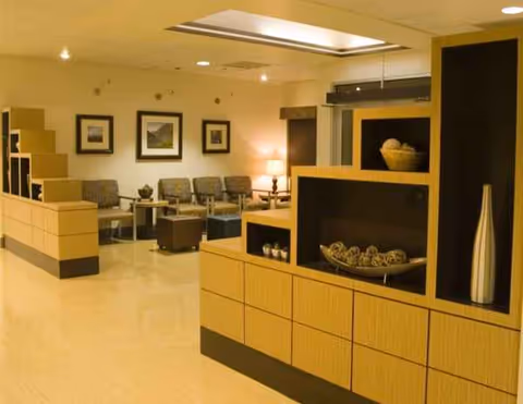 Modern senior living lounge with seating, wall art, and a reception area.