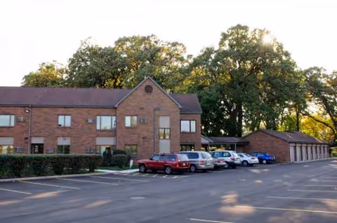 Brick senior living facility exterior with multiple parked cars and trees