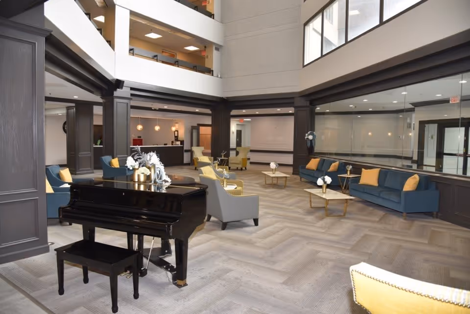Spacious two-story lobby/lounge with a black grand piano, multiple seating areas, and large windows.