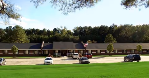 Front view of Durham Ridge Assisted Living building with parking lot and trees.