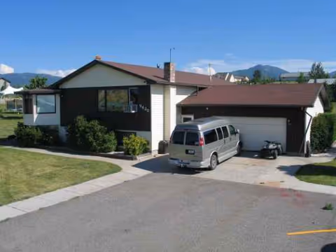 Exterior view of a single-story house with a two-car garage and a gray van parked.
