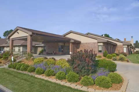 Front view of a brick senior living facility with landscaped entrance.