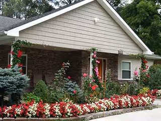 Front entrance of Orchard Manor with stone facade and colorful flower bed.