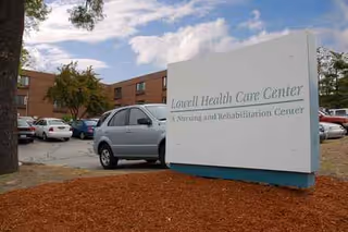 Exterior view of a care facility sign with parked cars in front