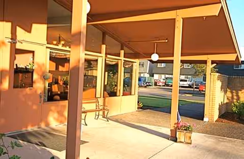 Regency Albany building entrance with a covered walkway, glass doors, and a bench.