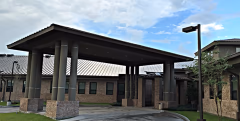 Front entrance of a brick senior care facility with a large covered porte-cochere and columns.