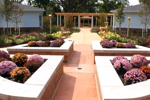 Symmetrical outdoor garden pathway with flowering planters leading to a pergola at Brecon Village