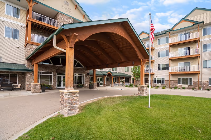 Exterior view of Savage Senior Living building with covered entrance and flagpole.