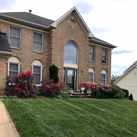 Front view of a brick senior living facility entrance with steps and landscaping.