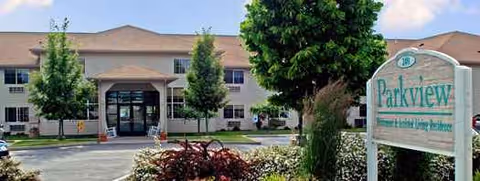 Front exterior of Parkview Senior Living with entrance, landscaping, and a welcome sign.
