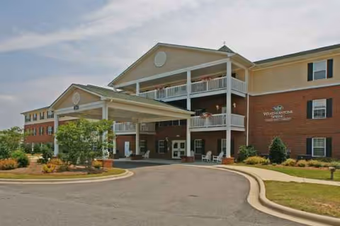 Exterior view of Weatherstone Spring senior living facility with a covered entrance and balconies.