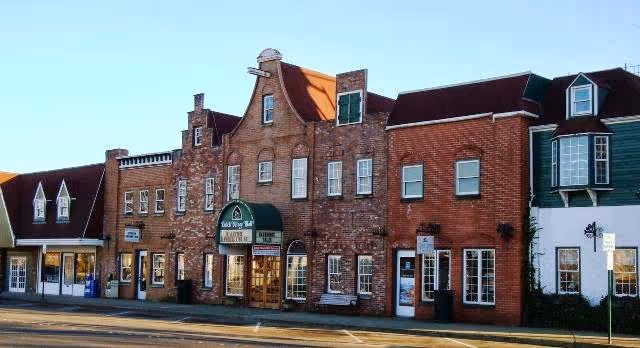 Street view of a brick building with a green awning labeled 'Christian Health Care Center' and multiple windows, situated between other buildings with varied architectural styles under a clear sky.