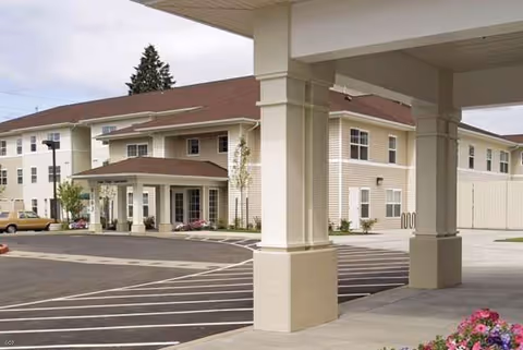 Exterior view of Arbor Ridge senior living facility with covered entrance and parking lot.