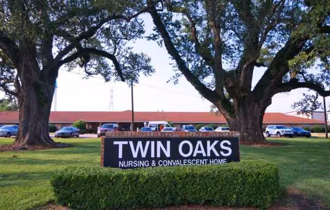 Twin Oaks Nursing & Convalescent Home sign on a manicured lawn with trees and building behind.