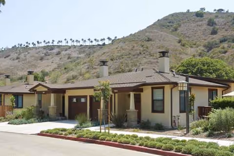 Exterior of a single-story senior living facility with beige walls and desert landscaping.