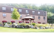 Brick rehabilitation facility building with gazebo, red canopies, and landscaped front lawn.