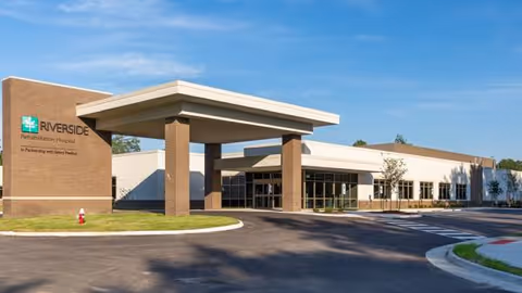 Exterior view of a modern senior living center with a covered entrance and parking.