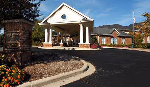 Front entrance of a senior living facility with a covered porte-cochere and landscaping.