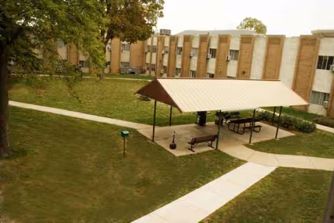Outdoor courtyard of a senior living facility with a covered pavilion and benches.