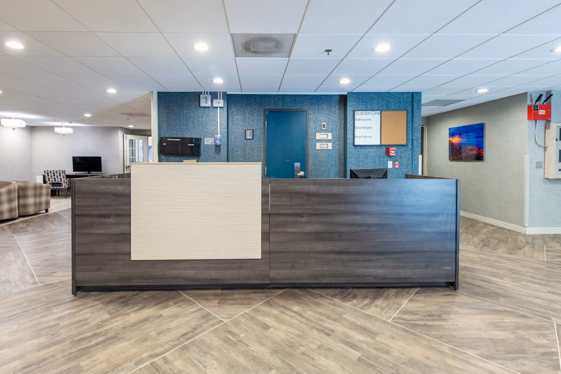 Reception desk and lobby area inside a senior living facility with seating visible to the left.
