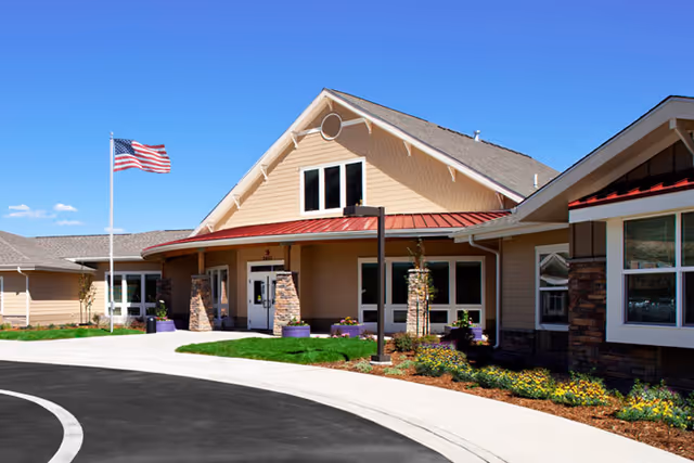 Front exterior view of MorningStar Memory Care at Bear Creek with entrance and flag.