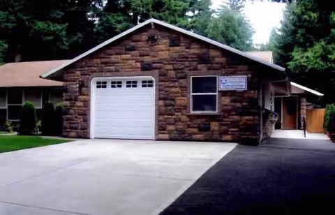 Stone exterior Angela Adult Care Home building with a garage and driveway.