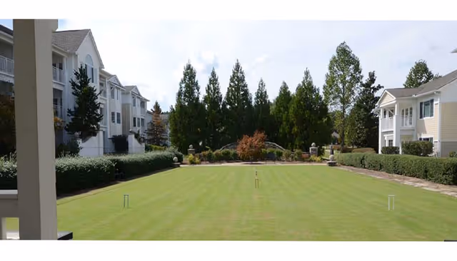Exterior view of a senior living community courtyard with manicured lawn and trees.