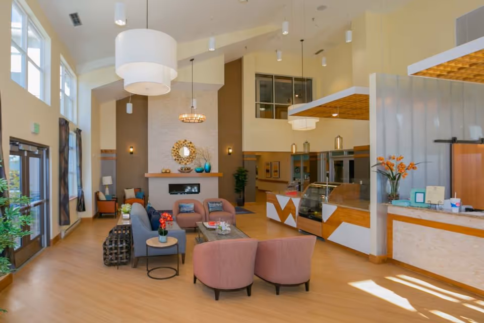 Bright, open common area with seating, a fireplace, and a reception/café counter.